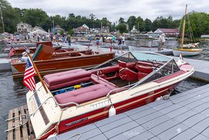 Red and white runabout with flag at the dock