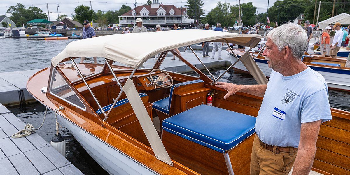A boat owner standing beside his canopy-top classic boat on the dock, ready to chat