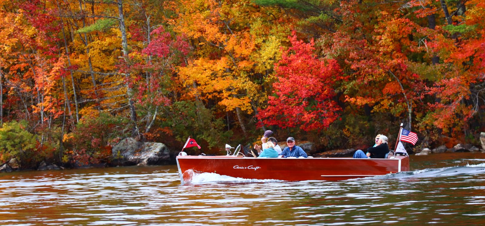 Club members cruising their classic boats past brilliant fall foliage