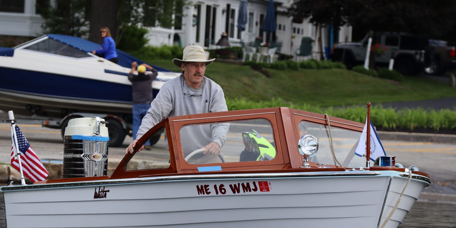 Club member standing at the wheel of his classic boat at the launch ramp